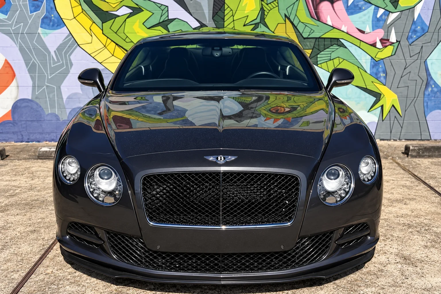 Front view of a dark Bentley with installed windshield outside the workshop.