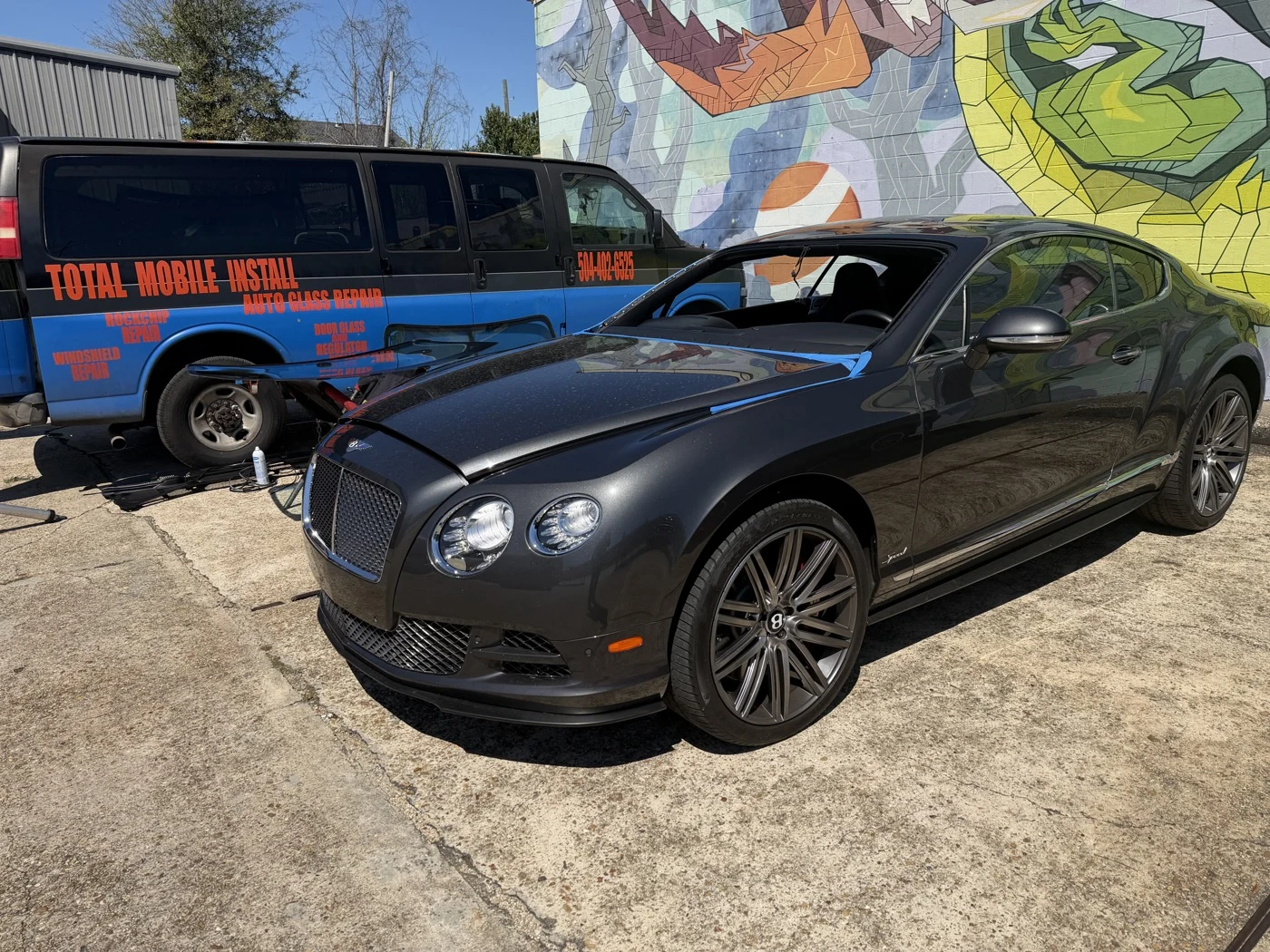 A Bentley outside the workshop beside the Total Mobile Install service van.